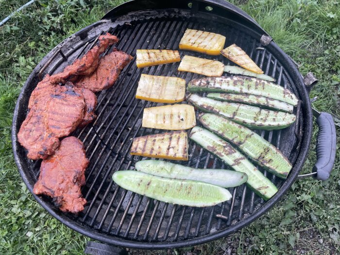 Grill med kött och grönsaker: zucchini, gurka; matlagning utomhus på kolgrill.