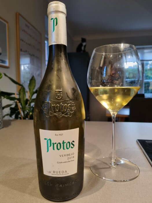 En vinflaska märkt "Protos Verdejo 2018" bredvid ett glas vin.