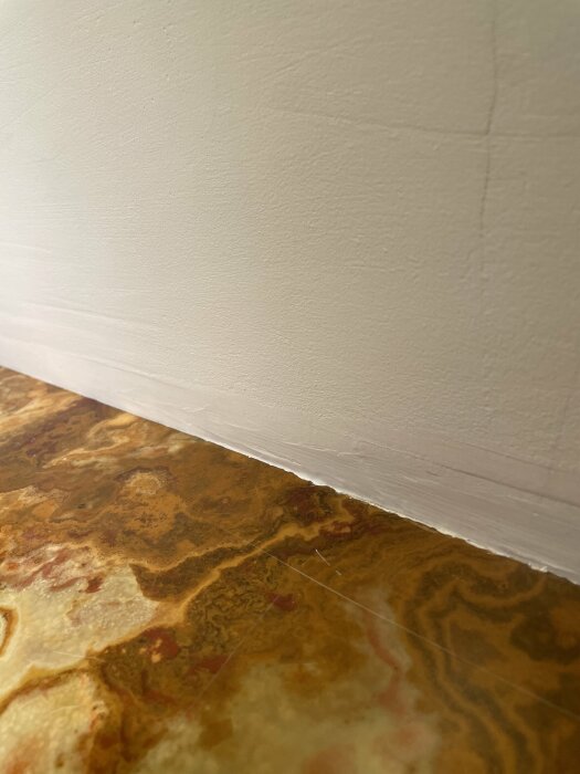 Väggmöte golv med dekorativ list och marmorerat golv, interiör detalj.