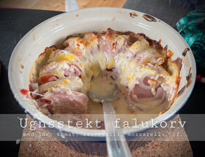 Gratinerad falukorv i form med lök, tomat, cheese, sweet chili-sås, delvis uppäten, hemlagad mat.