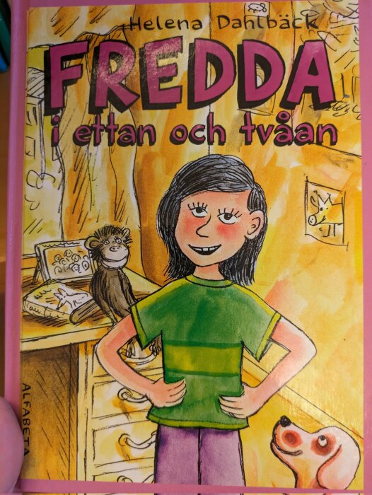 Omslag på en barnbok med en tecknad flicka, apa, och hund i ett färgglatt rum. "FREDDA i ettan och tvåan" står det.