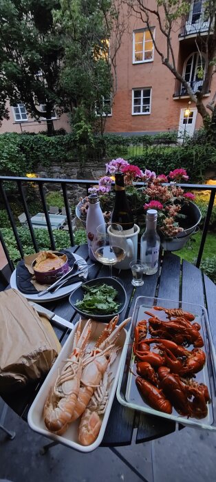 Mysig balkongmiddag med skaldjur, ostpaj, grönsallad och vin i en lugn stadsmiljö omgiven av grönska.