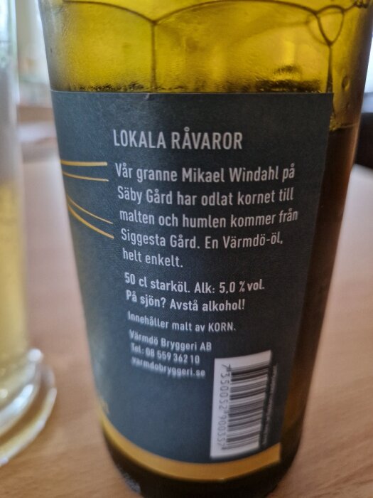 Etikett av dryckesflaska; lokala råvaror, Värmdö-öl, alkoholhalt 5.0%, Värmdö Bryggeri AB.