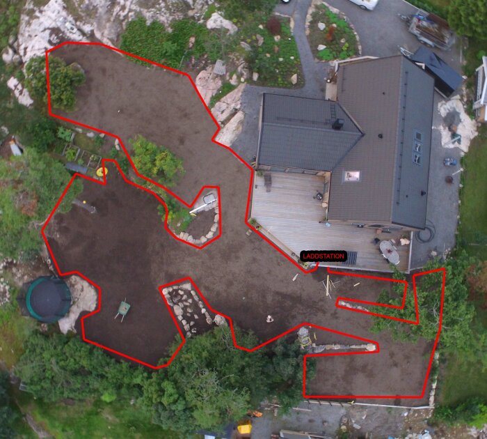 Flygbild av ett hus och trädgård, med markerade områden i rött, möjligen för planering.