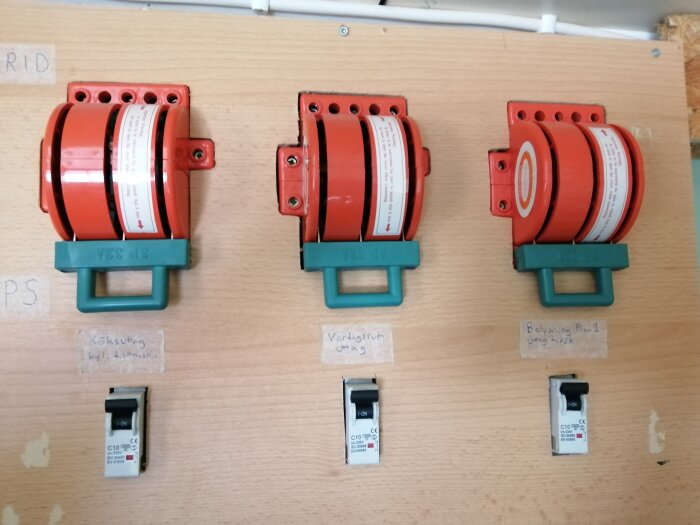 Tre industriella strömbrytare på vägg, etiketter för köksfläkt, värmeutrustning, belysning.