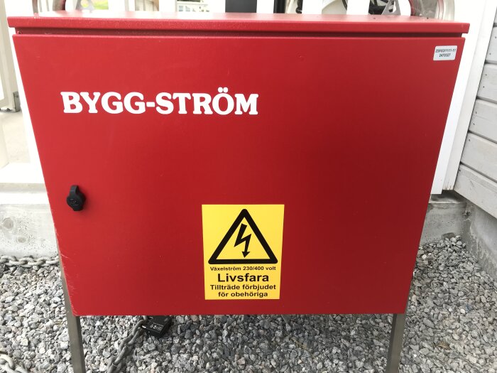 Röd elskåp märkt "BYGG-STRÖM", varningsmärke för högspänning, text "Livsfara", ingen åtkomst för obehöriga.