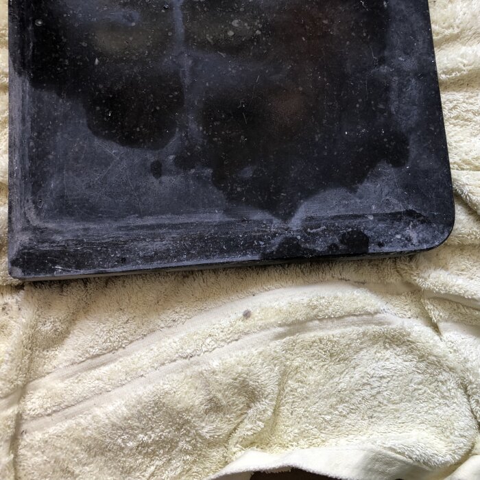 En smutsig, dammig laptop på en gulaktig handduk eller filt med tydliga användningsspår.
