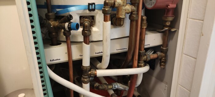 Rörsystem med kopplingar och ventiler inne i ett skåp, etiketterat för vattenledningar, inklusive kallvatten och expansionsledning.