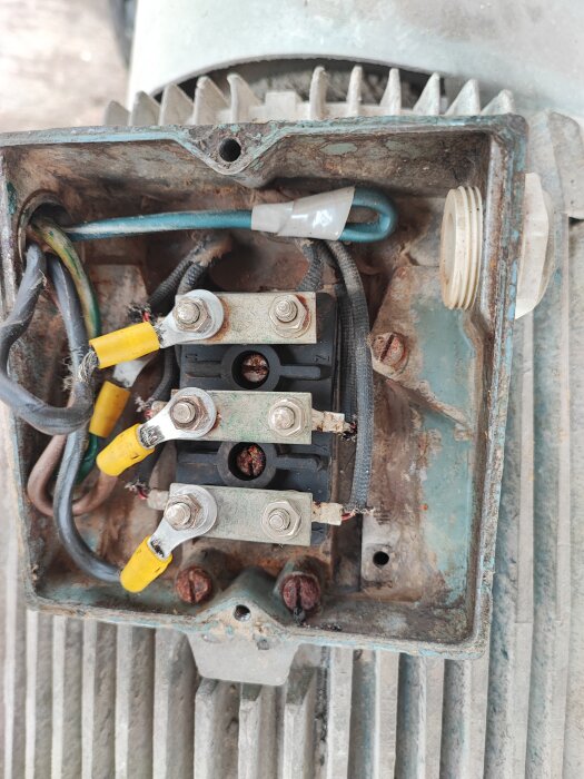 Äldre, rostig elektrisk anslutningslåda med kablar och anslutningsterminaler. Slitage och korrosion synligt.