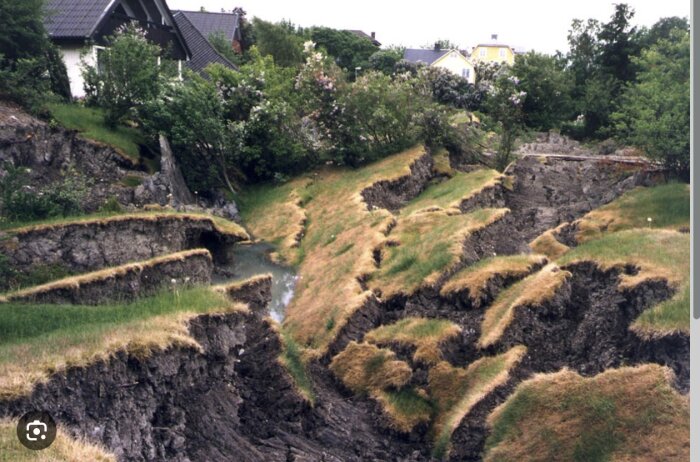 Jordbävningsskador, markbrott, hus i närheten, rämnade jordskorpan, farligt område, naturkatastrof, sänkt terräng.