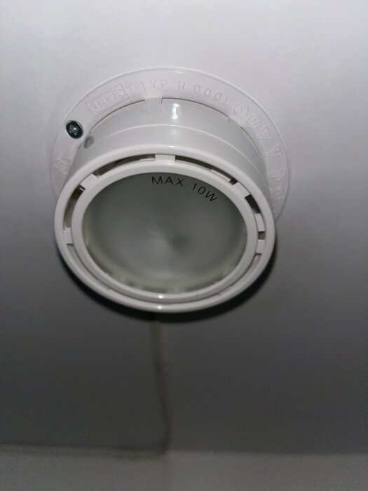 Ett tomt takfäste för ljuskälla, vit plast, märkt "MAX 10W", troligen för spotlight.