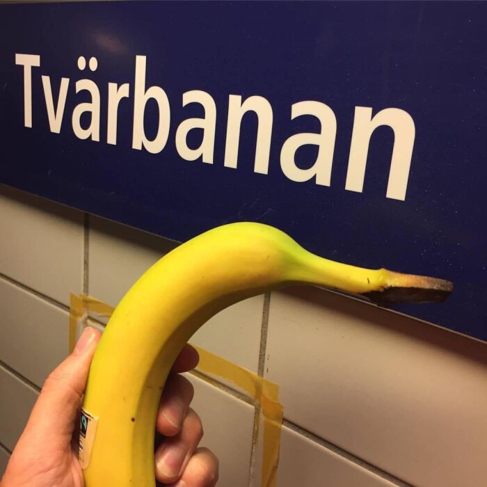 En banan hålls framför en skylt med texten "Tvärbanan", skapar en visuell ordlek.