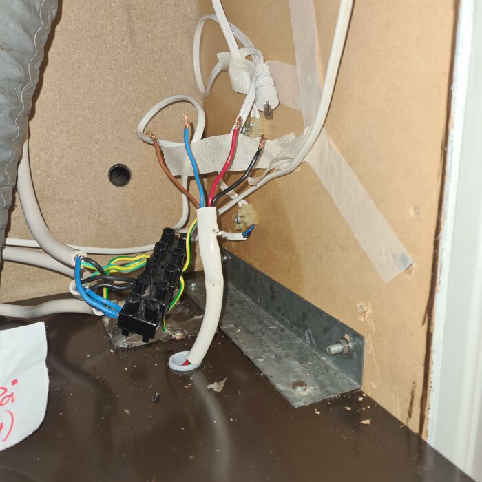 Oorganiserade, exponerade elektriska kablar och kopplingar inuti en vägg, säkerhetsrisk, oavslutat elarbete.