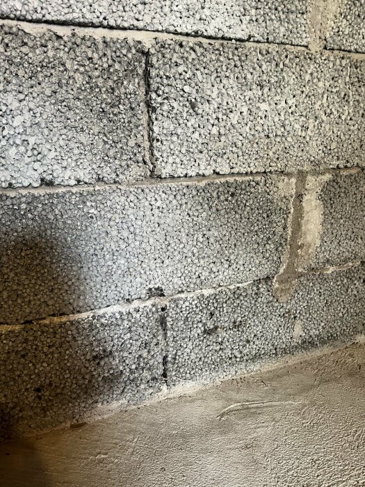 Texturerad grå betongblocksvägg och en del av ett golv i ett hörn.