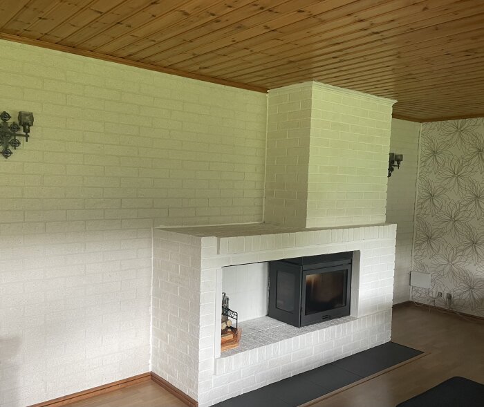 Vardagsrum med vit kakelugn, träpaneltak, ljus tapet, eldstad. Modernt, minimalistiskt, skandinavisk stil.