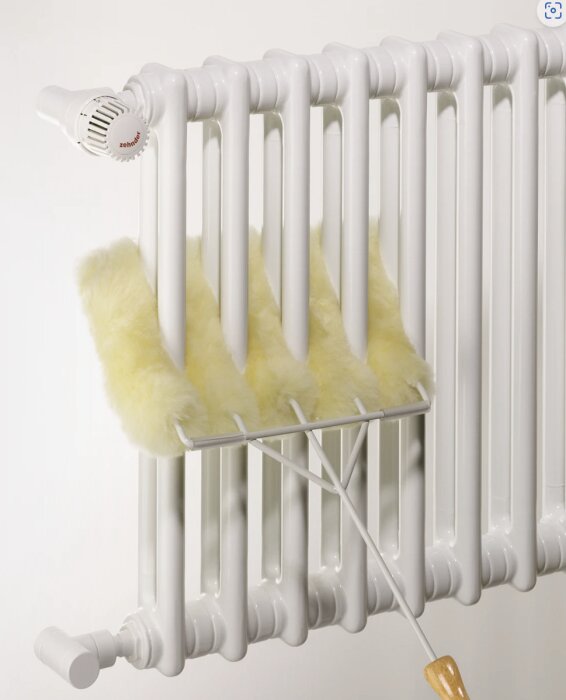 Vit elementradiator, guldlammfäll, hängare, träborste, neutral bakgrund.