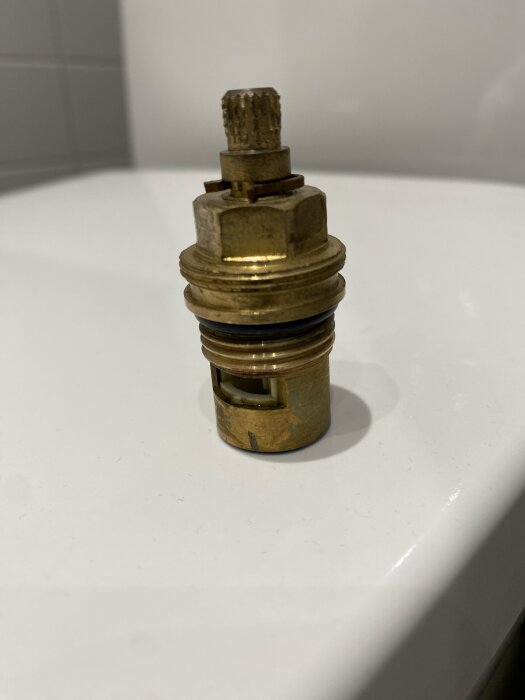 En begagnad mässingsventil på ett vitt underlag, möjligtvis från en vatteninstallation.