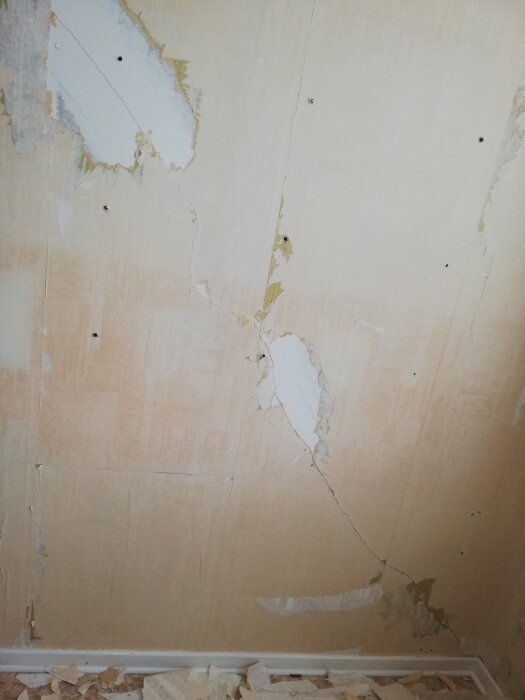 Slitna tapeter där delar rivits av avslöjar underliggande vägg, behov av renovering eller reparation synlig.