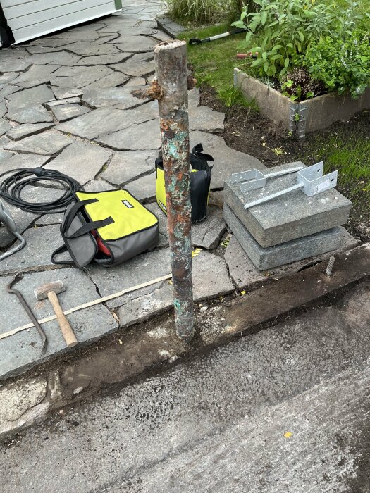 Arbetsyta utomhus med stolpe, verktyg, kablar och tomma el-boxar; tyder på pågående installation eller reparation.
