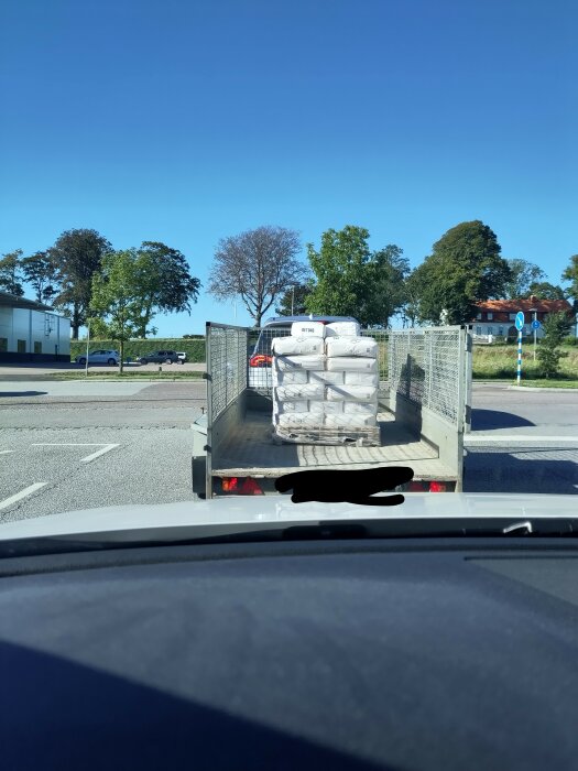 En lastbil lastad med säckar på en solig dag, sett från en bil.