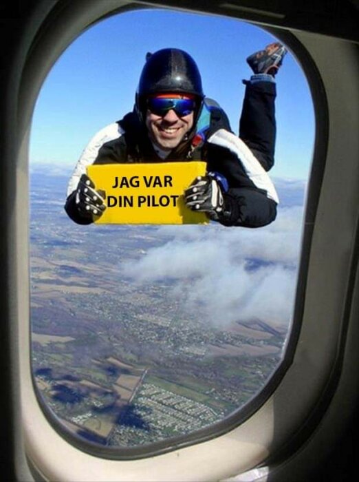 En person i fallskärmshjälm och goggles håller en skylt som skämtsamt säger "Jag var din pilot" utanför flygplansfönster.