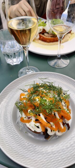 Måltid på tallrik med löjrom, gräddfil, rödlök, dill; skumpan och vattenglas; maträtt utomhus på restaurang.