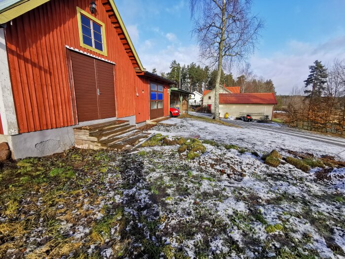 Röd stuga, snöfläckar, blå himmel, molniga landsbygd, bar mark, skugga, träd, klart väder, byggnader, lugnt.