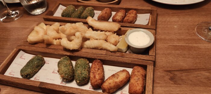 Träbrickor med friterade snacks, såsom croquetas och mozzarellasticks, serverades med dipsås och citron.