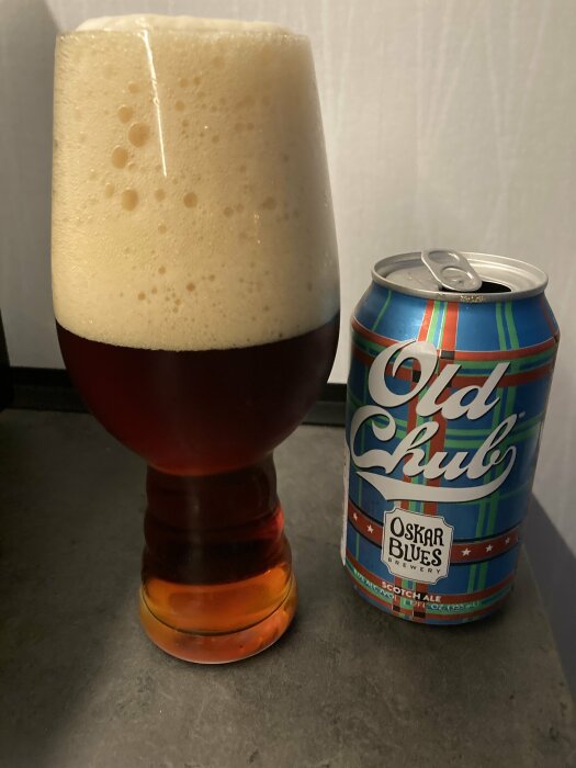 Ett ölglas överfyllt med skum bredvid en tom burk Old Chub Scotch Ale.