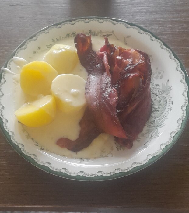 En tallrik med potatis, sås och ett stycke kött.