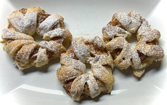 Flätor av smördeg på fat, strödda med florsocker, gyllene och bakade. Möjligtvis söta bakverk eller dessert.