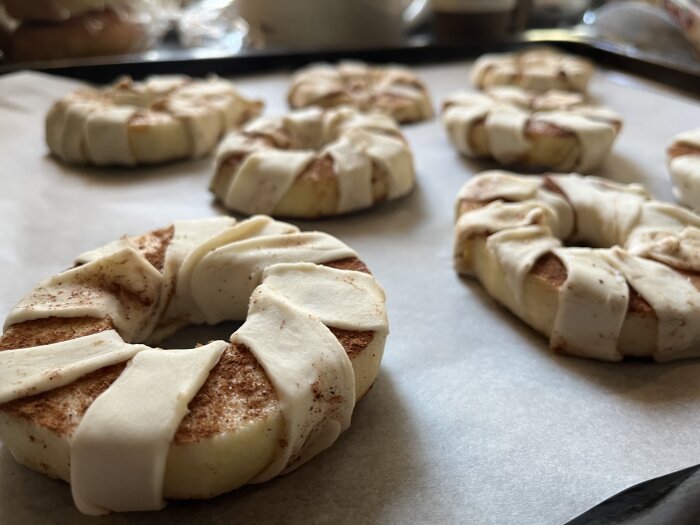 Okokta kanelbullar på bakplåt, förberedda för gräddning, doppade i kanel och socker.