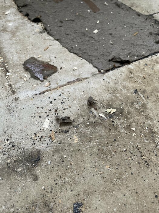 Förstörd asfalt och betong med sprickor och smuts på ett övergivet eller förfallet område.