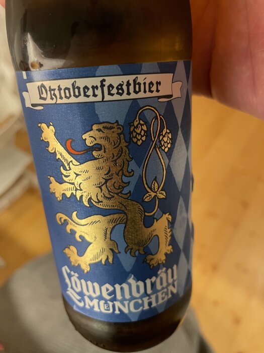 Ölflaska med etikett, "Oktoberfestbier," Löwenbräu München, heraldisk lejon, traditionellt, bayerskt, höstfestival-tema.