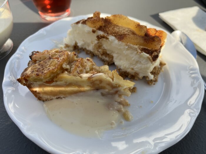 Två pajbitar på tallrik, äppelpaj med vaniljsås, cheesecake med kanel, efterrätt, utomhus.