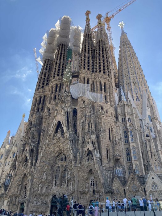 Sagrada Familia, Barcelona, under konstruktion, torn, skulpturer, kristen ikonografi, turister, klar himmel.