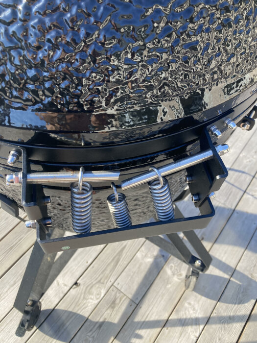 Keramisk grill med svart lock, högblank finish, fjädermekanism, på träaltan.