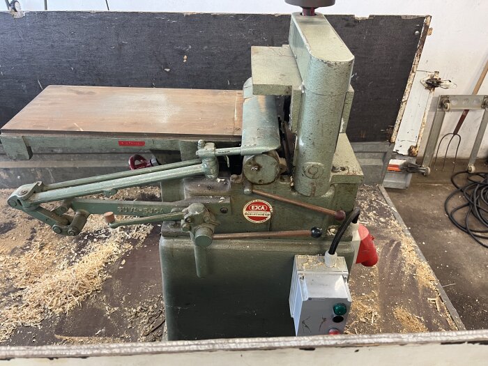 Gammal träbearbetningsmaskin, spånskrapor på bordet, verktyget är i ett snickeri.