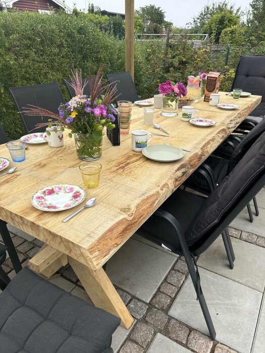 Utomhus dukat bord, trä, blommor, porslin, fika, stenplattor, trädgårdsstolar, natur, mysigt.