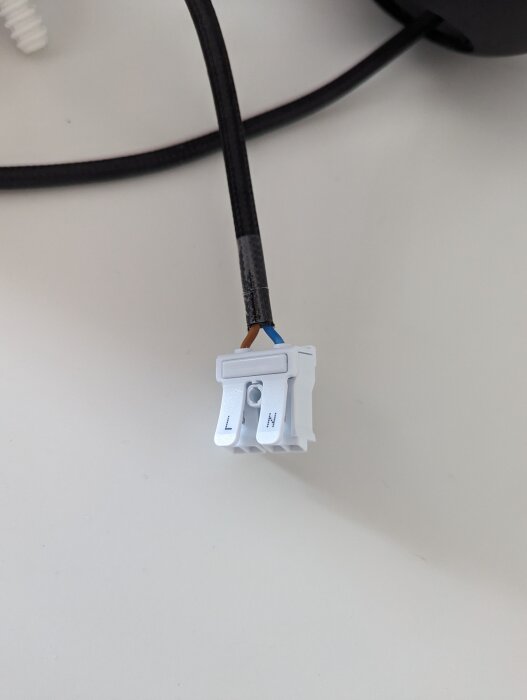 En elektrisk kabel med en oisolerad ände och en WAGO-kopplingsklämma mot en ljus bakgrund.