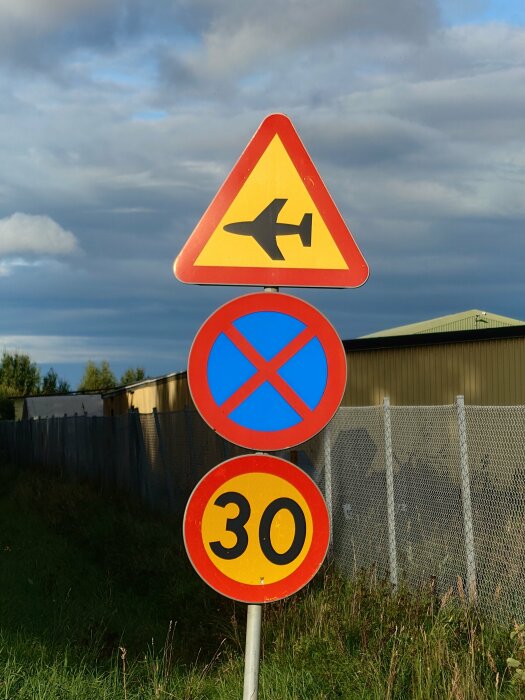 Trafikskyltar, varningsmärke för flygplansöverfart, parkeringsförbud och hastighetsbegränsning till 30 km/h.