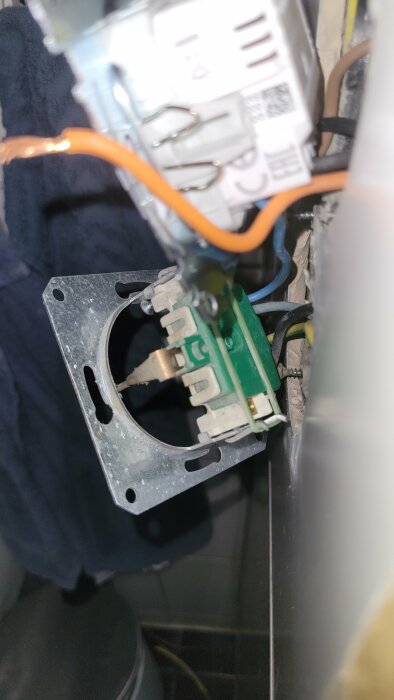 Närbild av en öppen elektrisk dosa med delvis monterad strömbrytare och oskarpa delar.