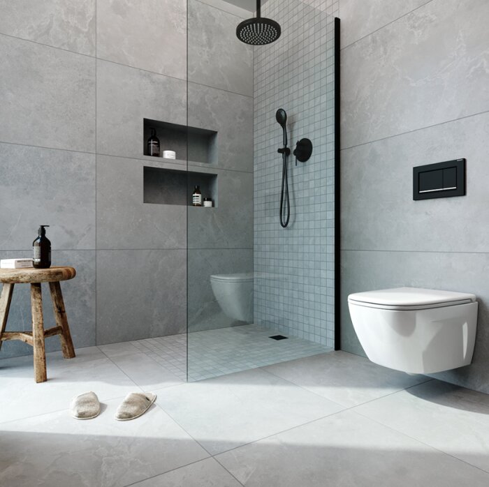 Modernt badrum med duschhörna, grå kakel, hängande toalett, trästol och badtofflor.