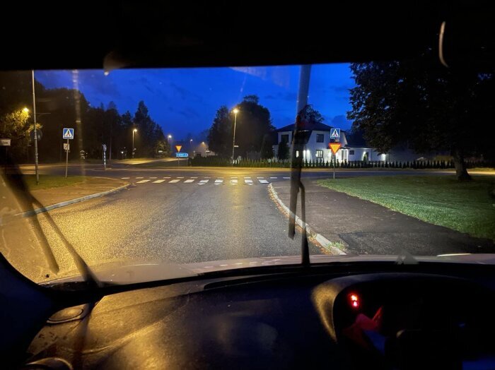 Nattvy från en bil, gatubelysning, övergångsställe, skymning, vägskyltar, tom gata, vindrutetorkare.