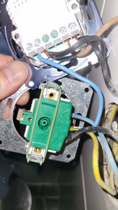 Installation av eluttag, person kopplar elektriska ledningar, säkerhetsrisk om ej kvalificerad, oavslutat elektriskt arbete.