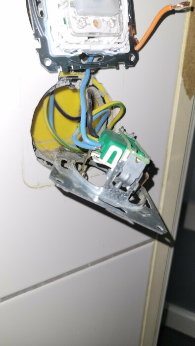 Öppen elinstallation, eluttag demonterat från vägg, synliga kablar och ledningar, risk för elektrisk fara.