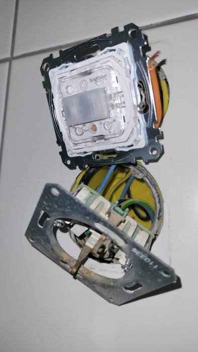 Öppen ljusströmbrytare med kabelanslutningar, utanpåliggande installation mot kakelvägg, av märket Schneider Electric.