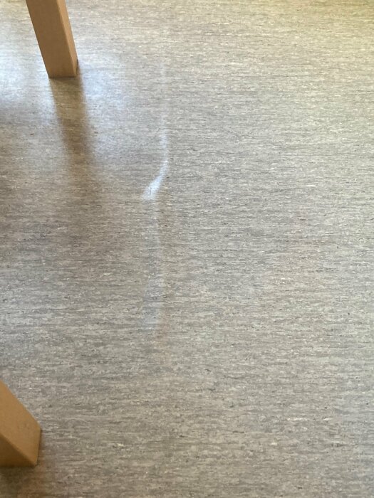 Trägolv med ben till möbel; suddig ljus reflektion eller repa synlig.