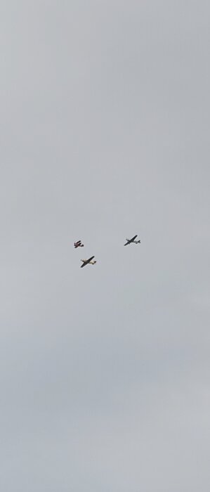 Fyra små flygplan flyger i formation mot en molntäckt himmel.