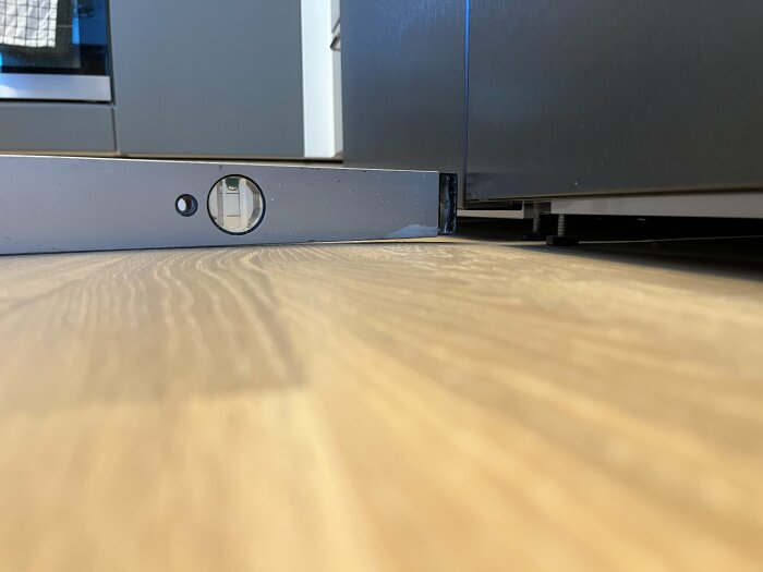 Nivåinstrument på golv för mätning, kontrollerar räthet vid installation av köksskåp.